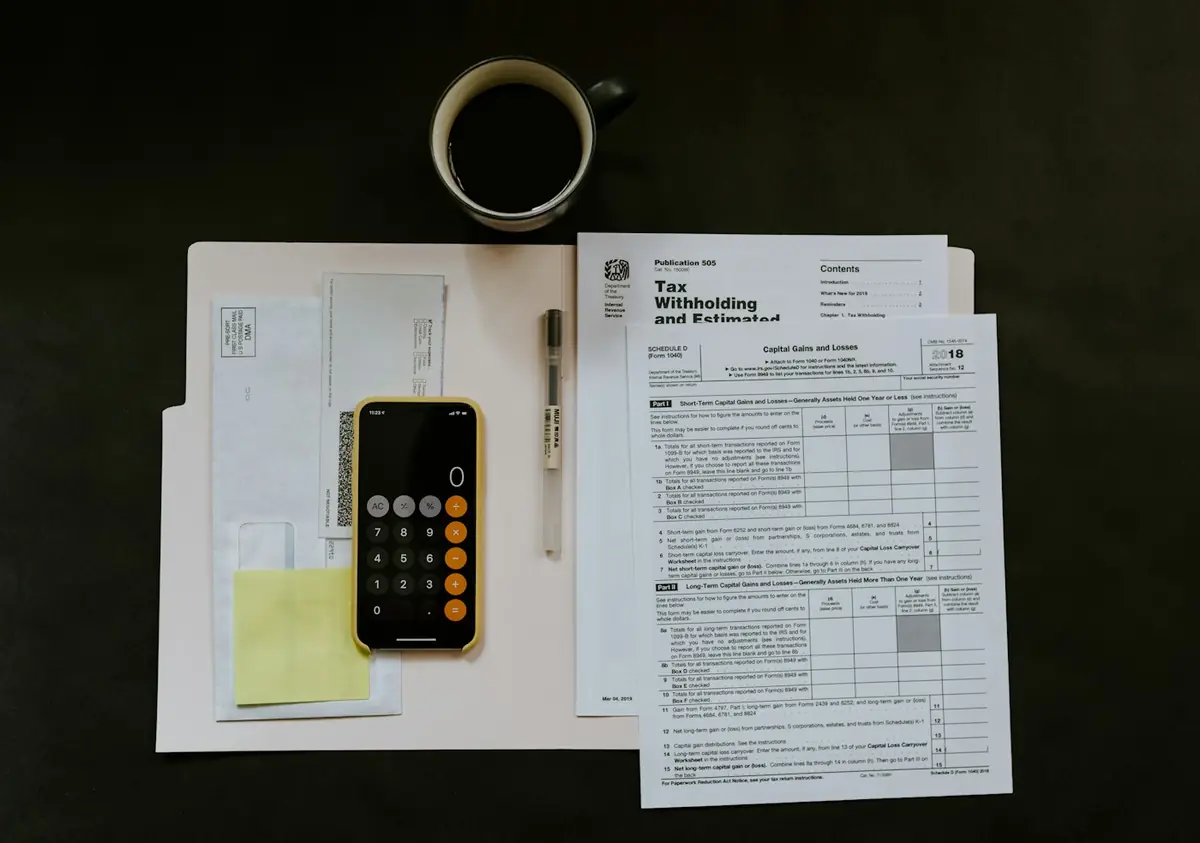 Tax forms, a calculator and a cup of coffee on a desk